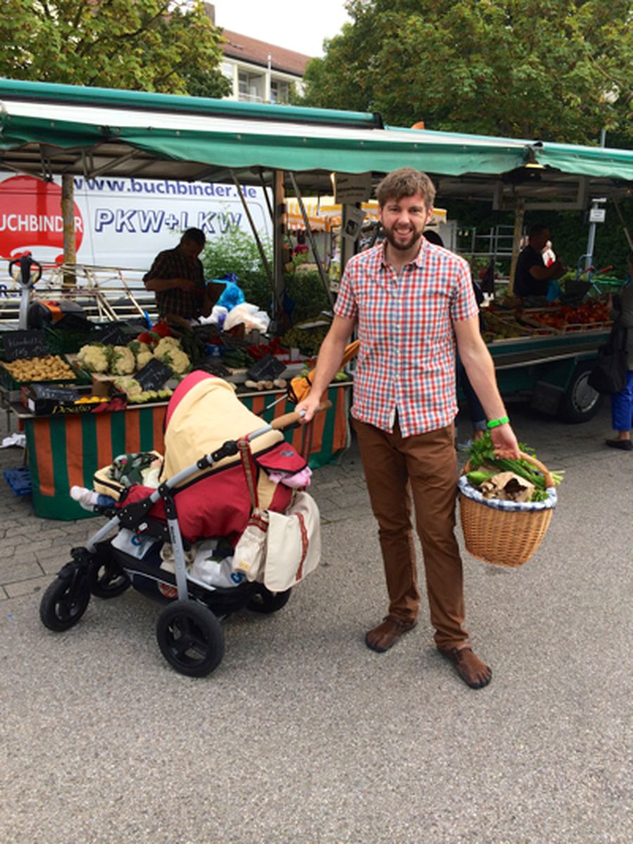 Pawel Konefal auf dem Wochenmarkt mit Einkaufskorb voller Gemüse und Kinderwagen